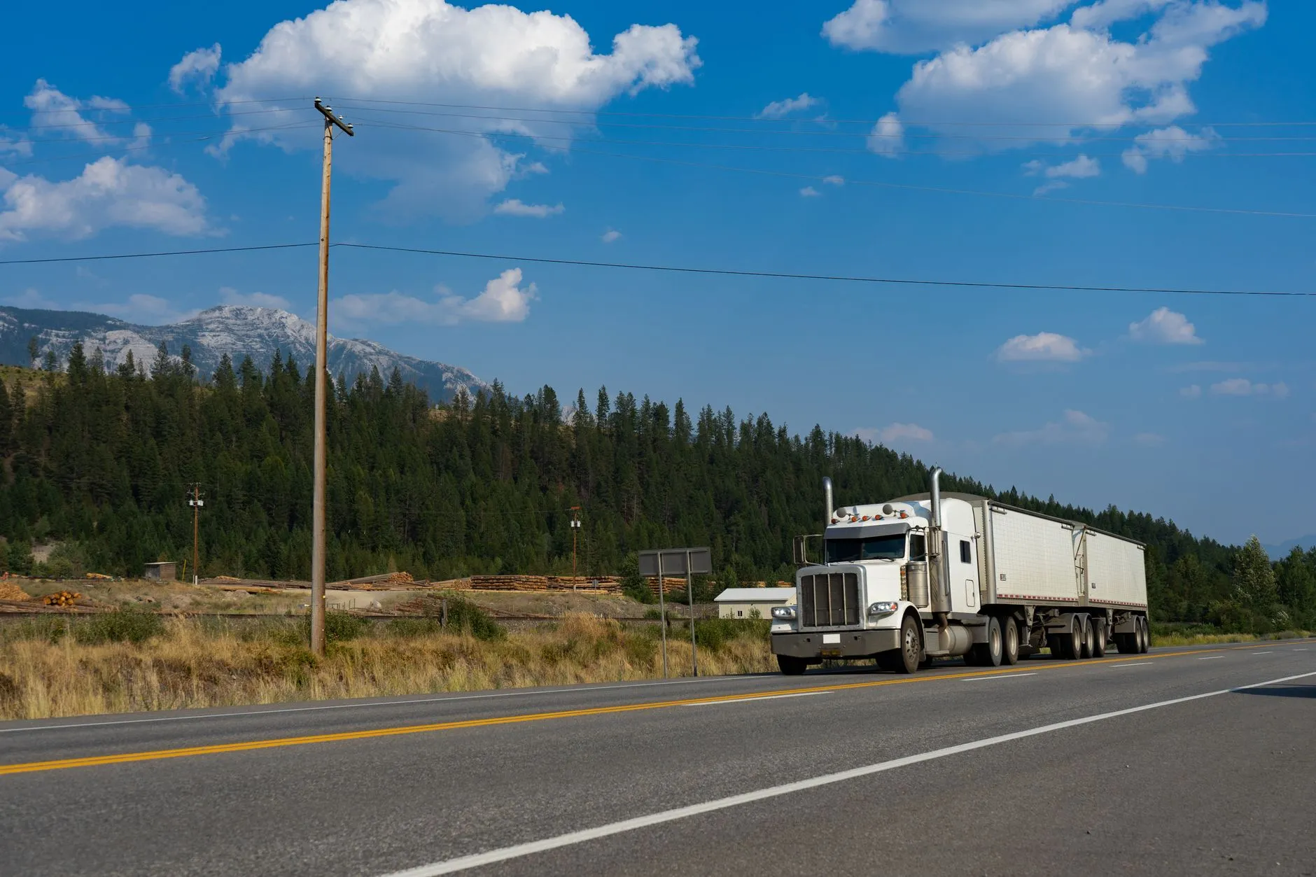 A transport truck on a highway through forested hills